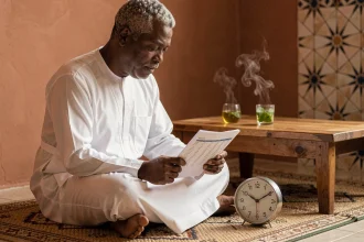 Homme consultant un tableau des horaires Imsak pour le jeûne du Ramadan dans un intérieur traditionnel