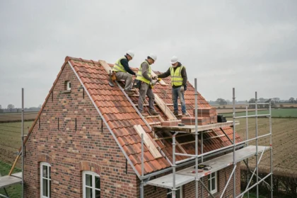 Équipe de couvreurs professionnels travaillant sur une toiture en tuiles d'une ferme traditionnelle dans les Hauts-de-France